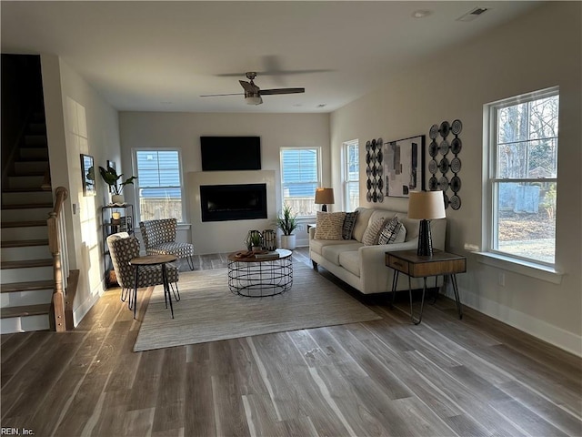 living room featuring visible vents, dark wood-style floors, stairway, a fireplace, and baseboards