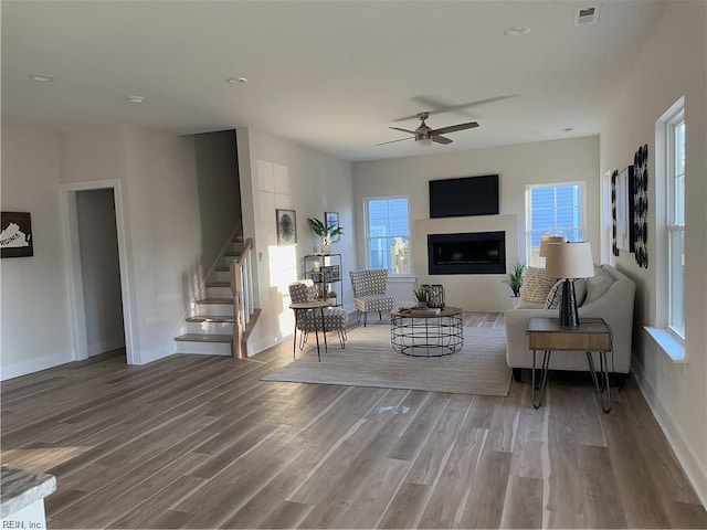 living room featuring stairs, wood finished floors, visible vents, and a fireplace