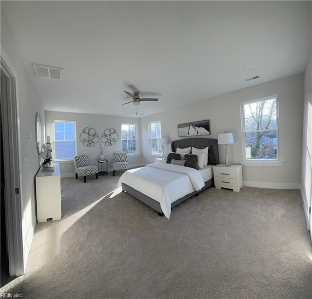 carpeted bedroom featuring visible vents, multiple windows, baseboards, and ceiling fan