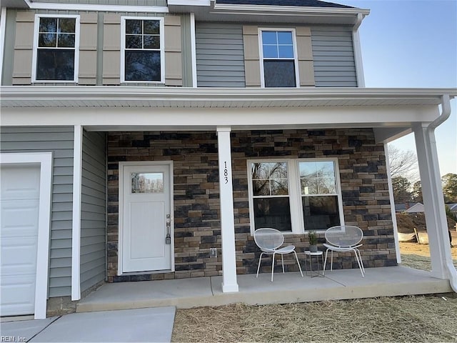 doorway to property featuring stone siding and a porch