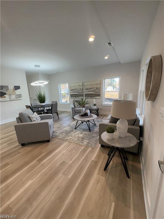 living room featuring recessed lighting, visible vents, baseboards, and light wood finished floors