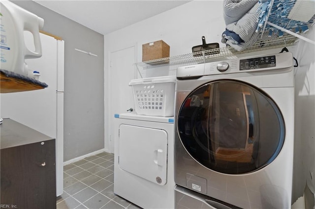 washroom with tile patterned floors, laundry area, washer and dryer, and baseboards