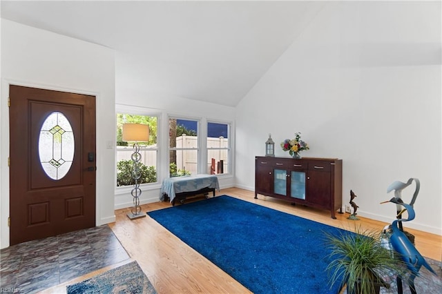 foyer featuring high vaulted ceiling, baseboards, and wood finished floors