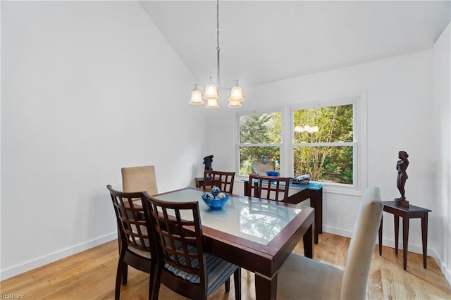 dining area featuring lofted ceiling, a notable chandelier, light wood-style floors, and baseboards