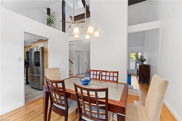 dining room with baseboards, high vaulted ceiling, stairs, light wood-style floors, and a chandelier