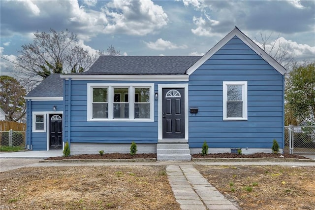 bungalow with a gate, fence, and roof with shingles