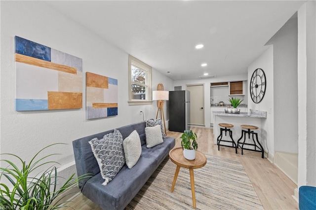 living area featuring recessed lighting, light wood-type flooring, and baseboards