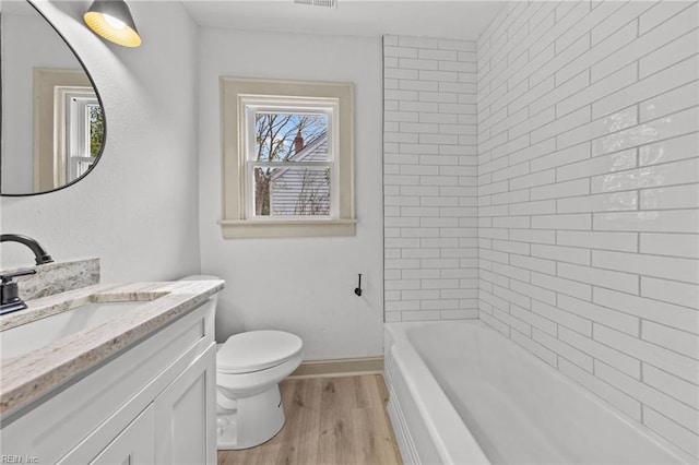 bathroom with vanity, toilet, wood finished floors, and baseboards