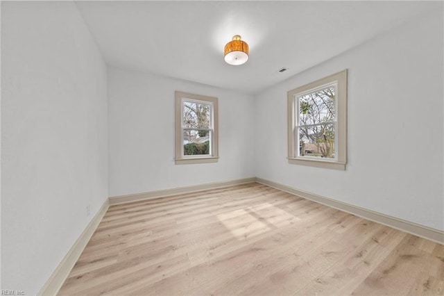 spare room with plenty of natural light, wood finished floors, and baseboards