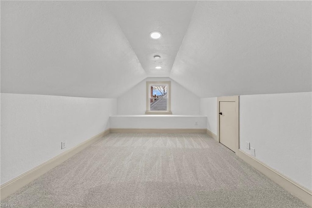 bonus room with carpet flooring, a textured ceiling, baseboards, and vaulted ceiling