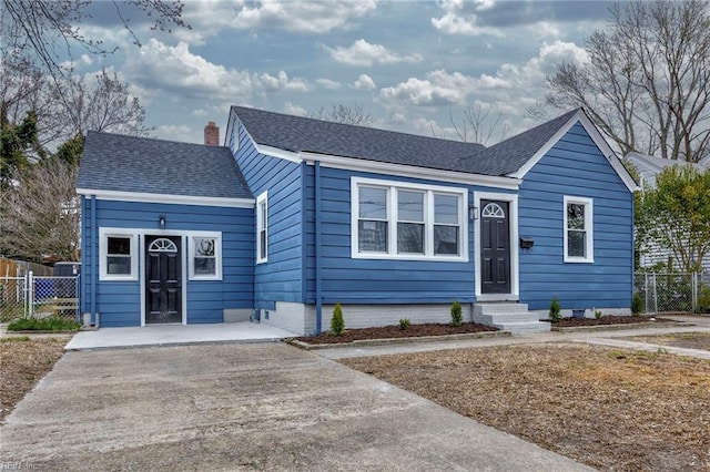 ranch-style home featuring entry steps, fence, roof with shingles, and a chimney