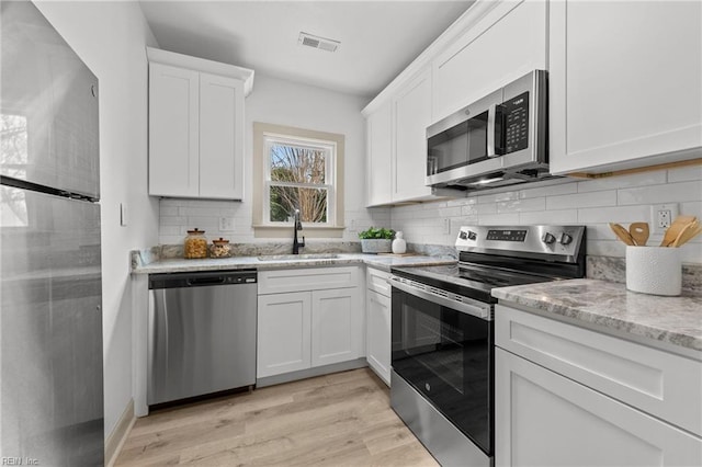 kitchen featuring visible vents, white cabinetry, stainless steel appliances, and a sink