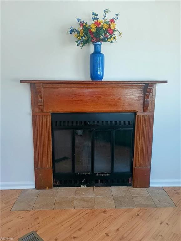 details featuring baseboards, a fireplace with flush hearth, and wood finished floors