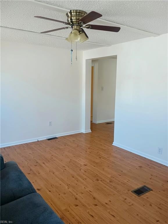 unfurnished living room with visible vents, baseboards, a textured ceiling, and wood finished floors