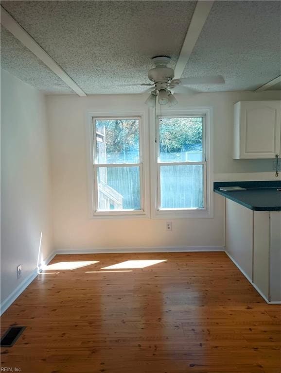 unfurnished dining area featuring a healthy amount of sunlight, light wood-type flooring, and baseboards