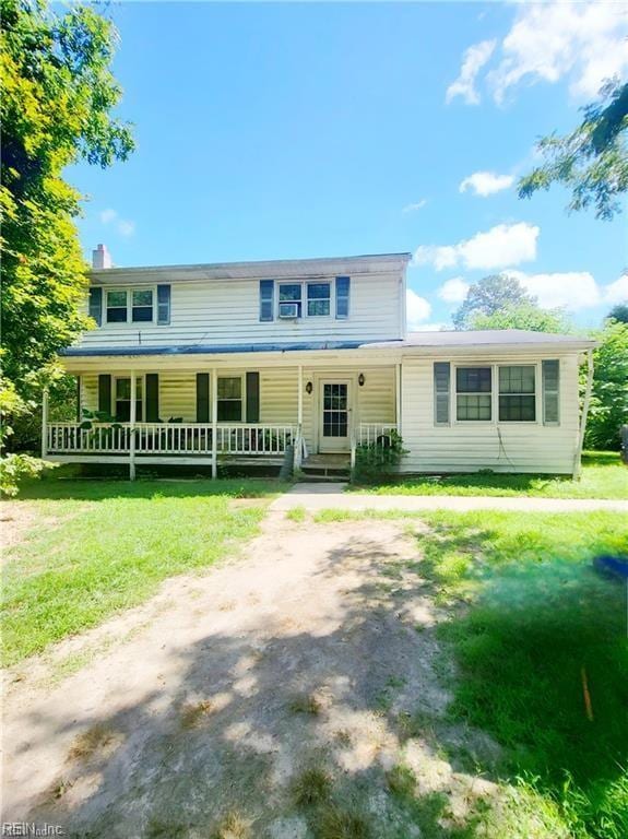 view of front of property featuring a front lawn, covered porch, and dirt driveway