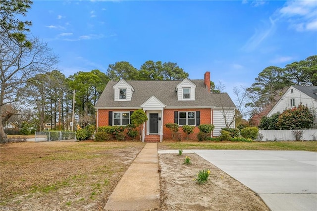 cape cod house featuring a front yard, fence, brick siding, and roof with shingles