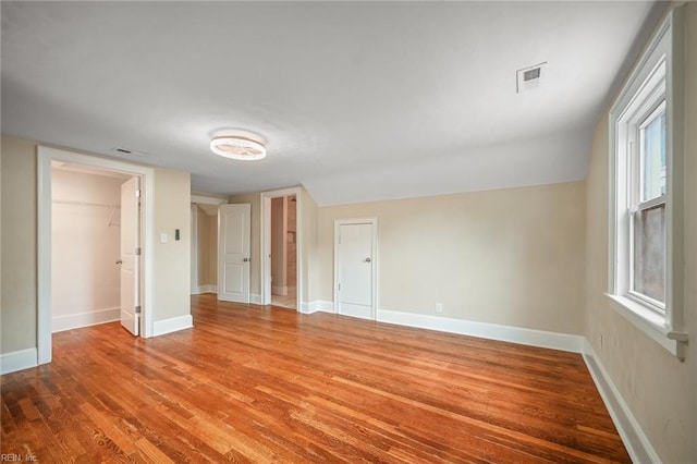 spare room with wood finished floors, baseboards, and a healthy amount of sunlight