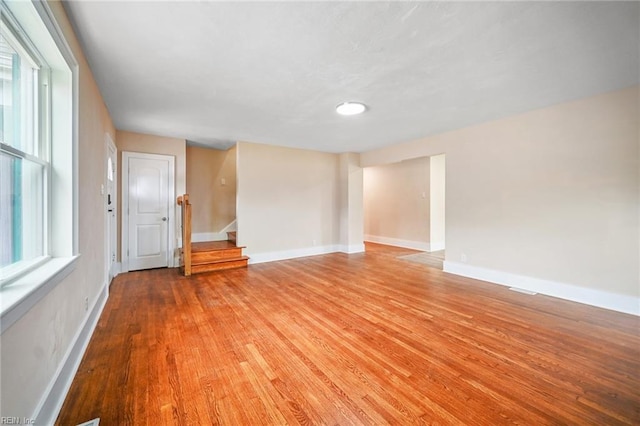 spare room with stairs, baseboards, and light wood finished floors