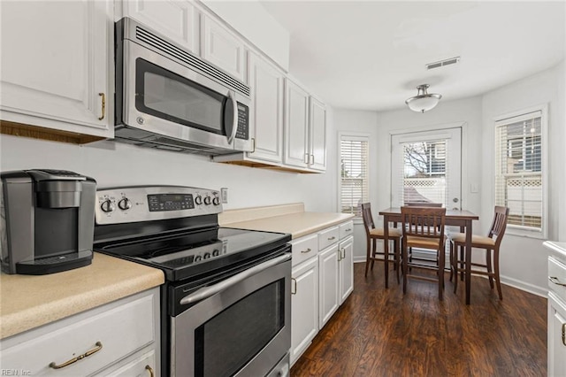 kitchen with visible vents, dark wood-style flooring, light countertops, white cabinets, and appliances with stainless steel finishes