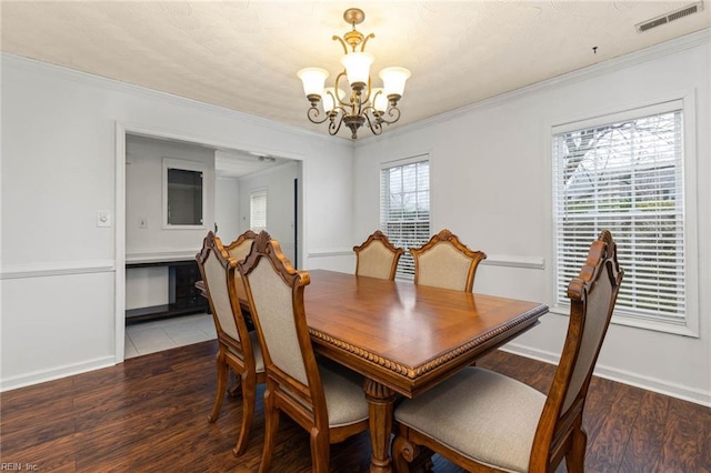 dining room with a notable chandelier, visible vents, crown molding, and wood finished floors