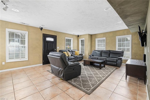 living area with light tile patterned flooring, visible vents, a textured ceiling, and baseboards