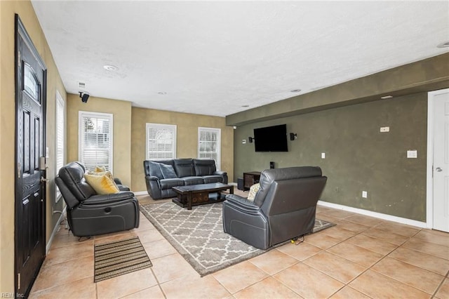 living room featuring light tile patterned flooring, a textured ceiling, and baseboards