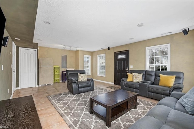 tiled living area with electric panel, plenty of natural light, baseboards, and visible vents