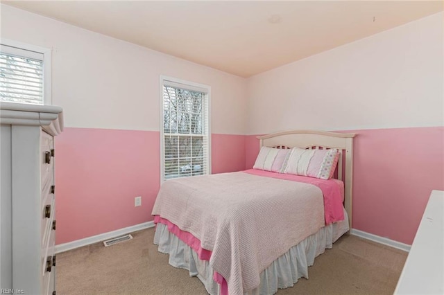 carpeted bedroom with visible vents, multiple windows, and baseboards