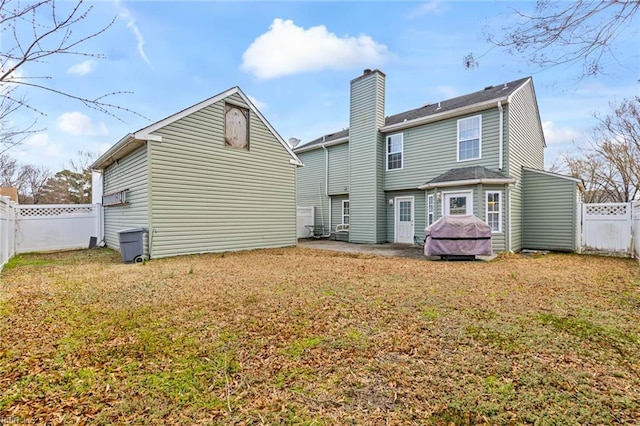 back of property with a patio, a lawn, a fenced backyard, and a chimney