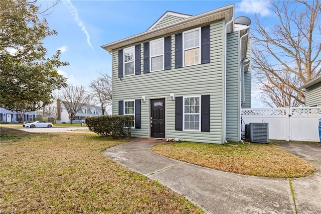 colonial-style house with central air condition unit, a front yard, and fence