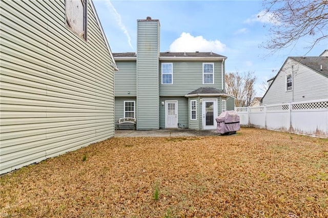 rear view of house featuring a patio area, a fenced backyard, a lawn, and a chimney