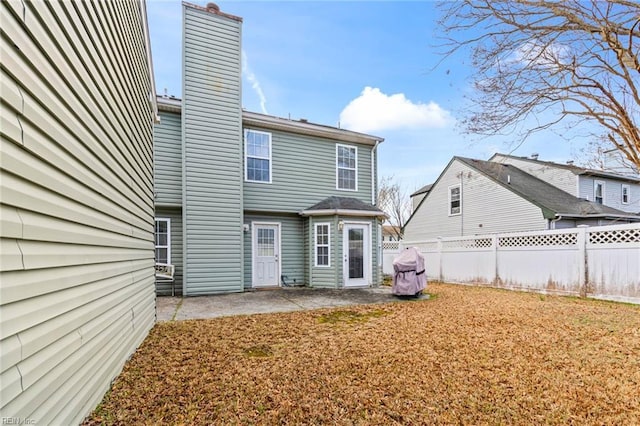 back of house featuring a patio area, fence, and a chimney