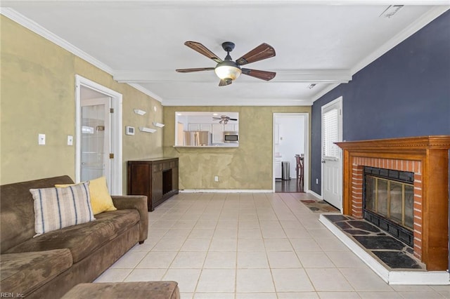 living area with tile patterned floors, ornamental molding, a ceiling fan, a fireplace, and baseboards