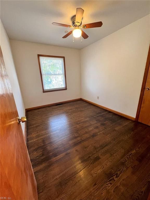 spare room with a ceiling fan, baseboards, and dark wood-style flooring