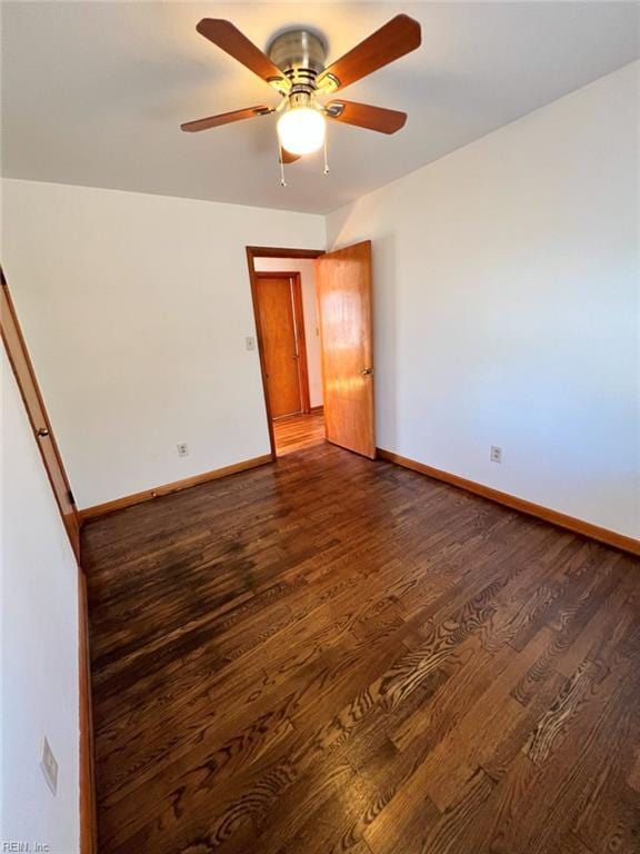 empty room featuring dark wood finished floors, a ceiling fan, and baseboards