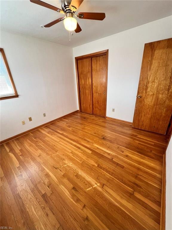 unfurnished bedroom featuring a closet, a ceiling fan, baseboards, and light wood finished floors