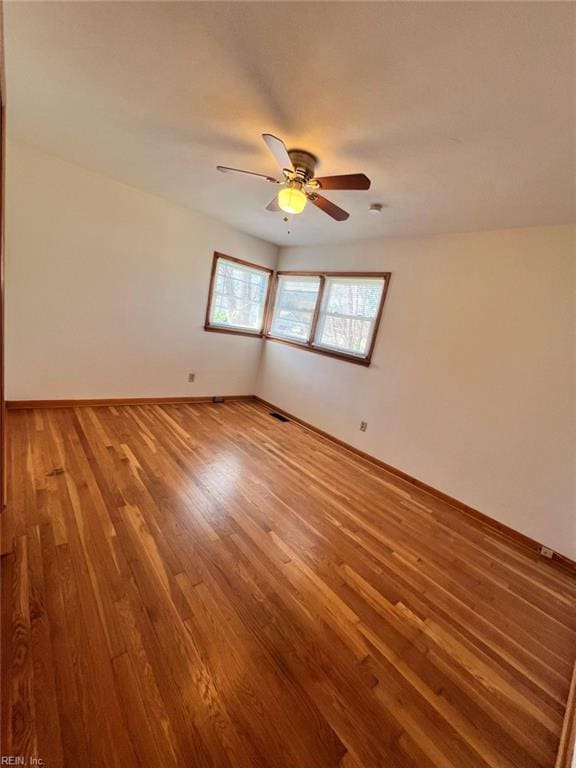 empty room featuring visible vents, a ceiling fan, light wood-type flooring, and baseboards