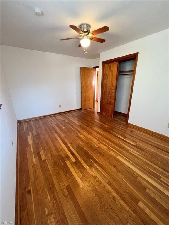 unfurnished bedroom featuring a ceiling fan, wood finished floors, a closet, and baseboards