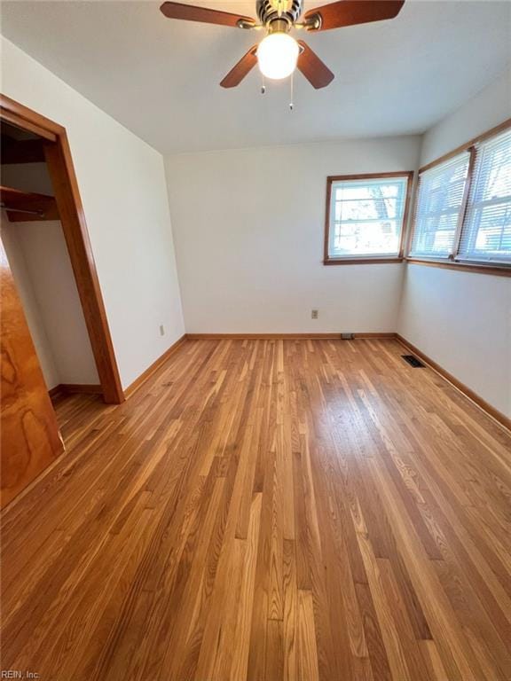 unfurnished bedroom featuring light wood finished floors, visible vents, ceiling fan, baseboards, and a closet