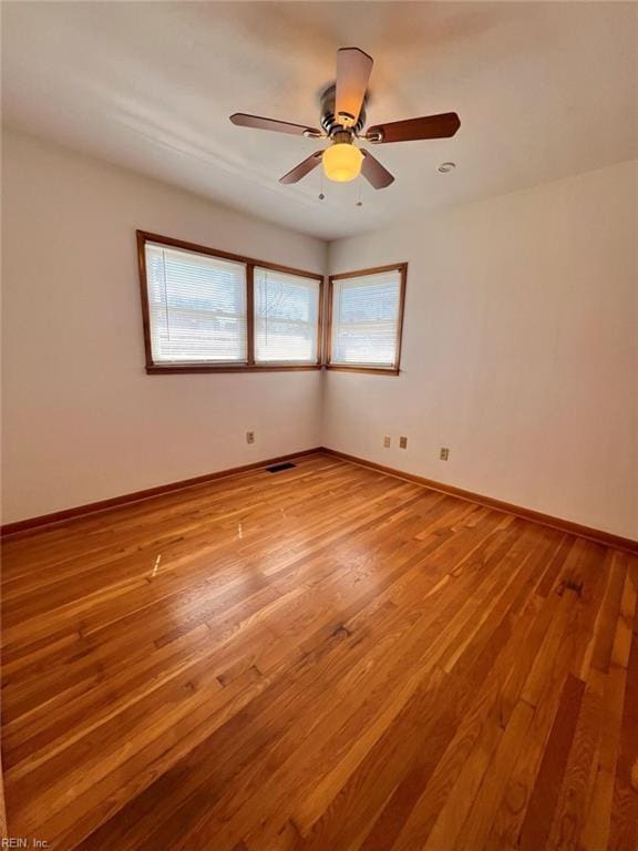 spare room featuring ceiling fan, light wood-style floors, visible vents, and baseboards