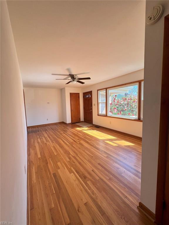 unfurnished room with baseboards, a ceiling fan, and light wood finished floors