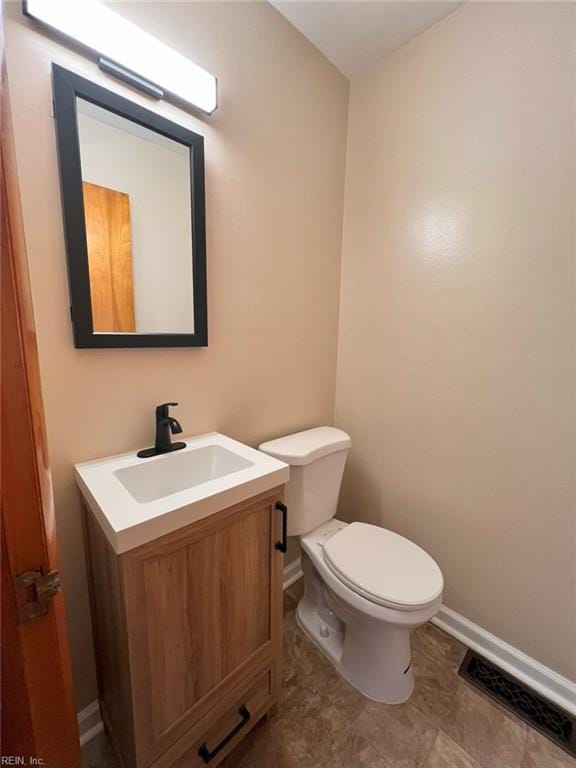 half bathroom with vanity, toilet, baseboards, and visible vents