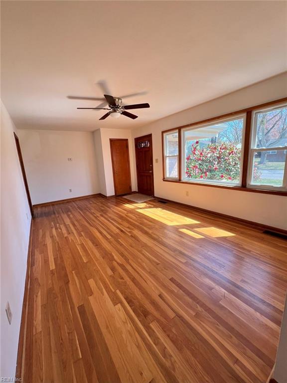 unfurnished room with a ceiling fan, wood finished floors, and baseboards