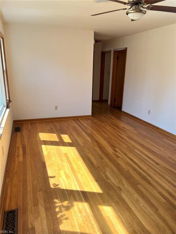 unfurnished room with visible vents, a ceiling fan, baseboards, and wood finished floors