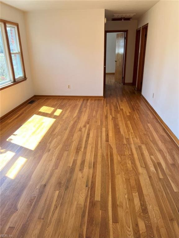 spare room featuring wood finished floors, visible vents, and baseboards