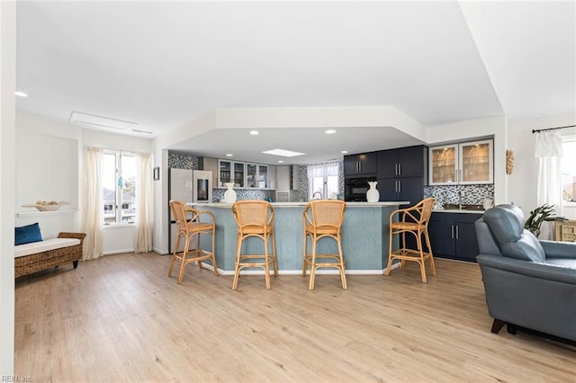 kitchen featuring decorative backsplash, refrigerator, a breakfast bar area, and glass insert cabinets