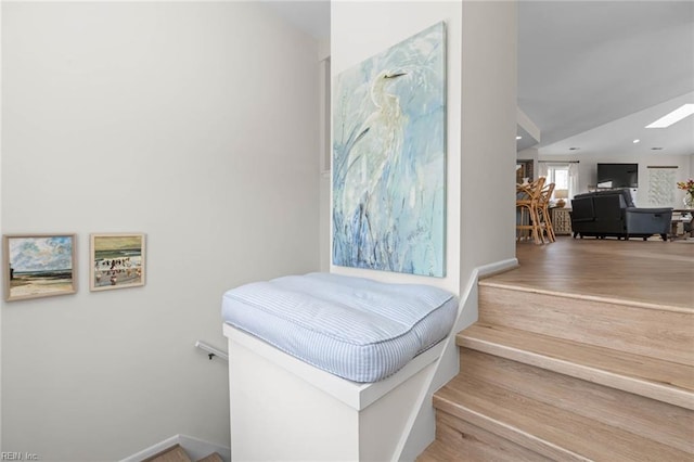 staircase with a skylight, baseboards, and wood finished floors