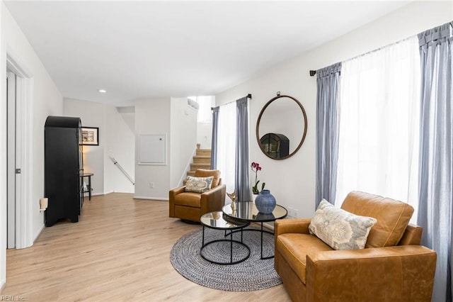 living area featuring stairs and light wood-style flooring