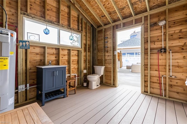 misc room featuring a sink, lofted ceiling, light wood-style floors, and water heater